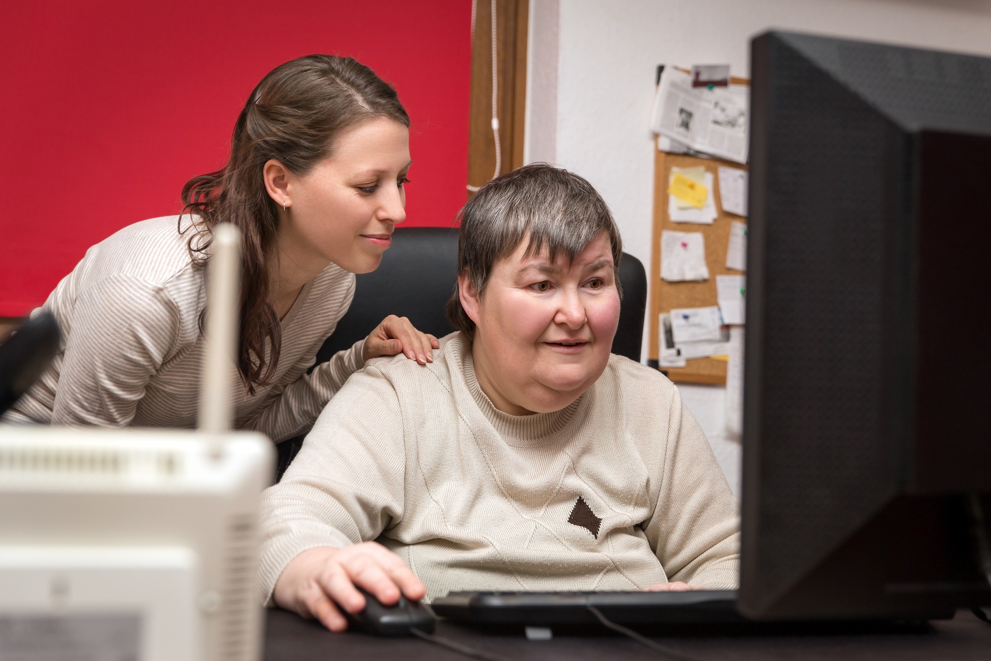 Betreuerin und geistig behinderte Frau lernen am Computer