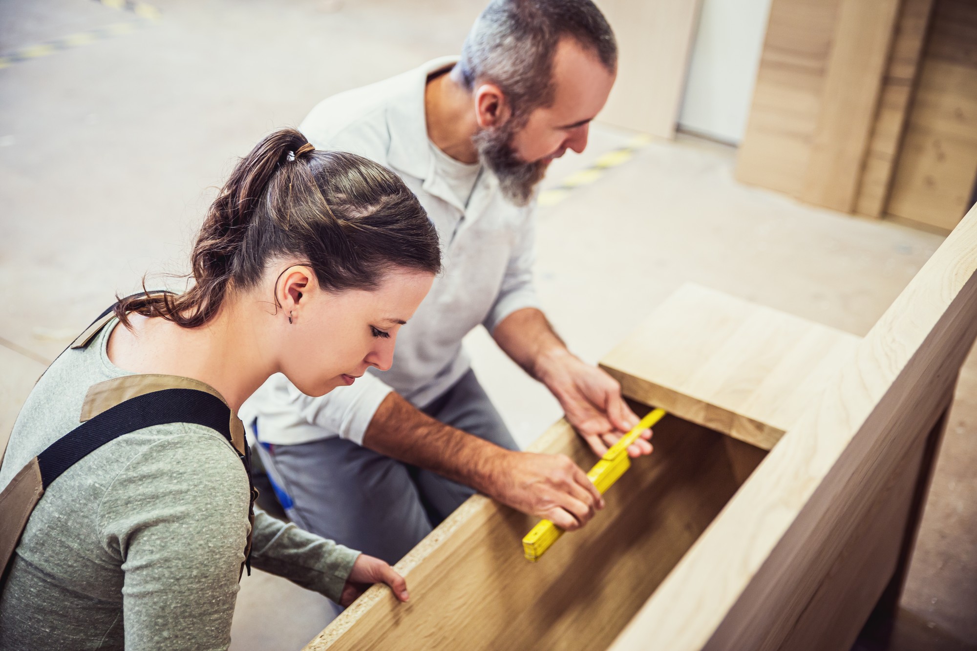 male and female carpenter at work, man and woman are crafting with wood in a workshop