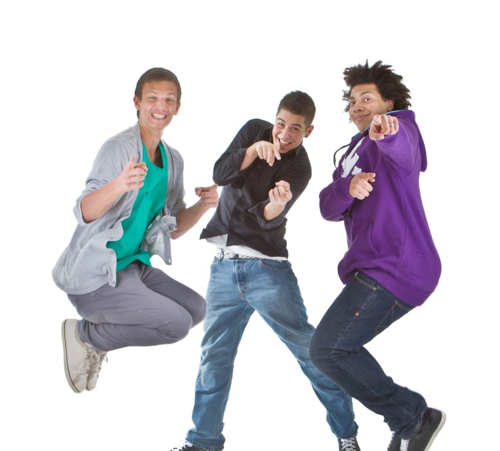 Three multiracial teenagers jumping over joy over white background.
