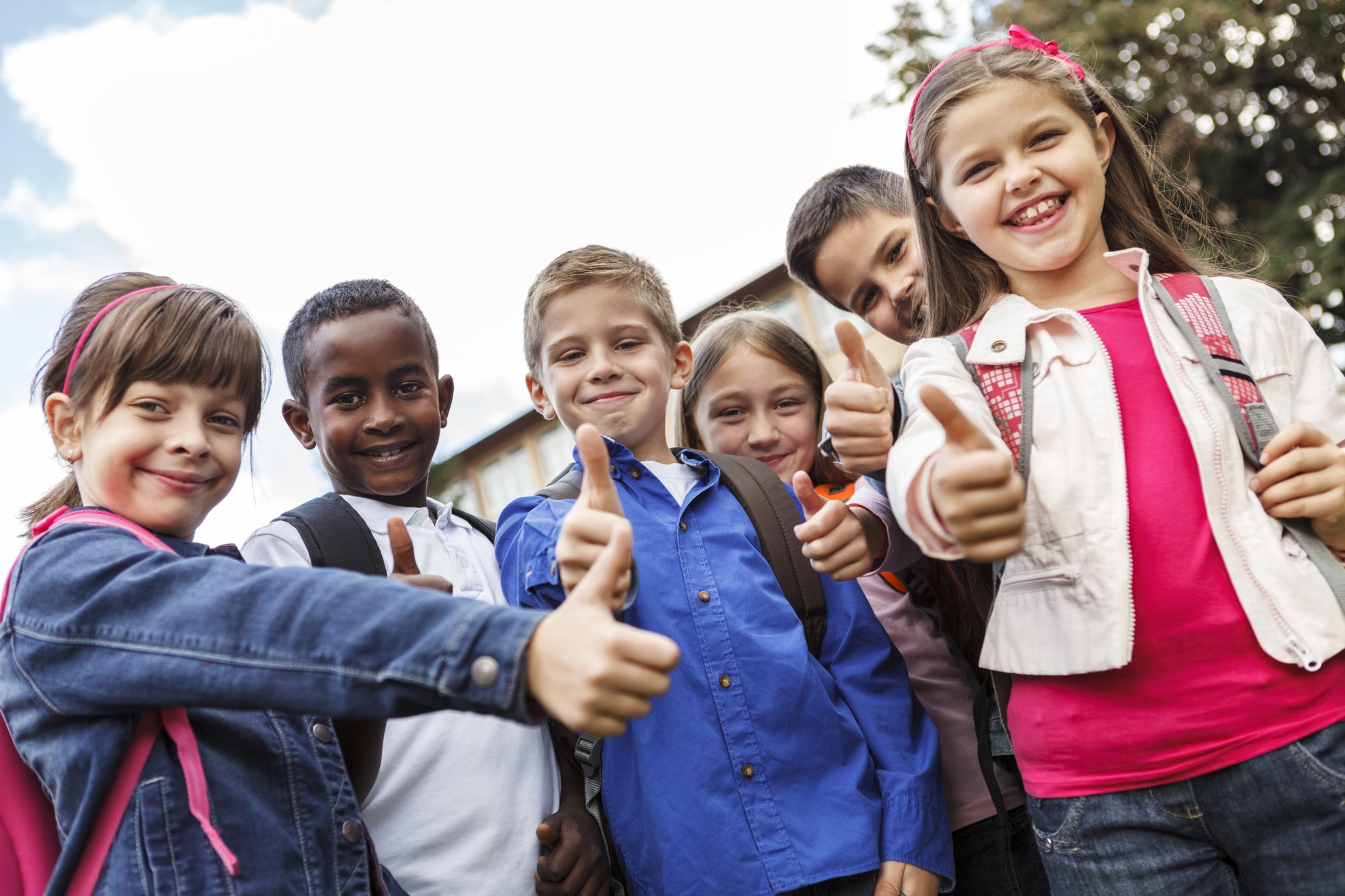 Group of mixed-race kids thumb up to camera