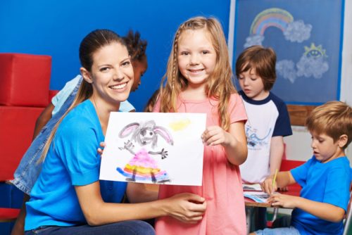 mdchen-zeigt-gemaltes-bild-im-kindergarten