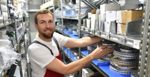 freundlicher-lagerist-in-einem-warenlager-fr-autoteile-friendly-storekeeper-in-a-warehouse-for-spare-parts
