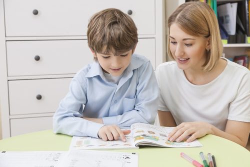 teacher-reads-a-textbook-with-a-boy-elementary-school-student
