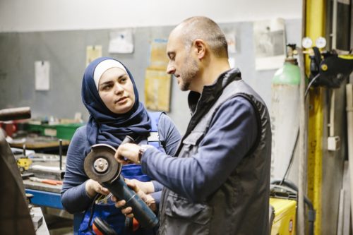 teamwork: technician explains a grinder to a female trainee in a workshop