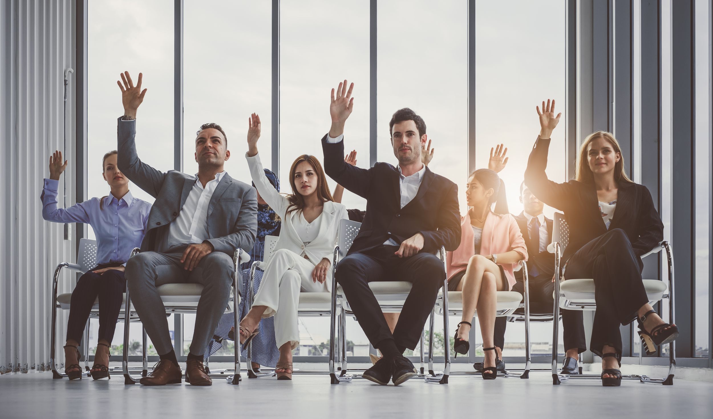 Group of business people raise hands up to agree with speaker in the meeting room