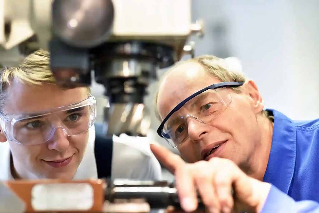 a man wearing safety goggles and looking at a machine