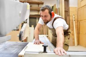 a man wearing headphones and working on a woodworking machine
