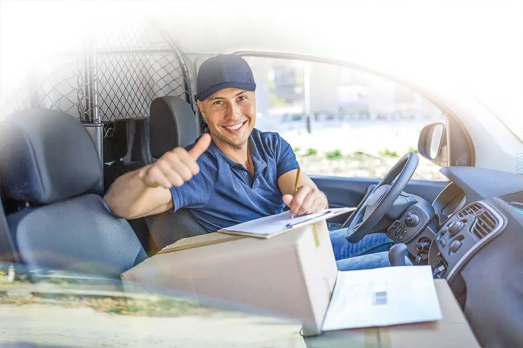 Junger Mann sitzt mit Paket im Lieferwagen