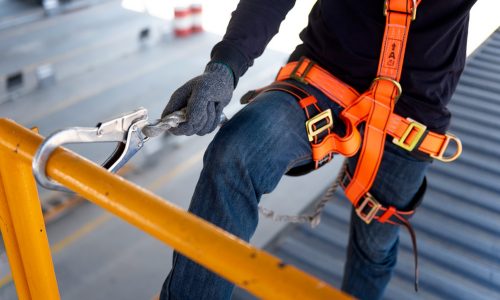 Construction worker use safety harness and safety line working on a new construction site project.