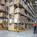A worker in a huge distribution warehouse with high shelves