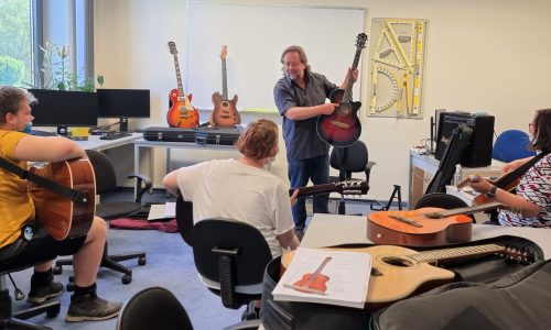 Musiker und Projektleiter Jens Dammann stellt Schülern eine Westerngitarre vor